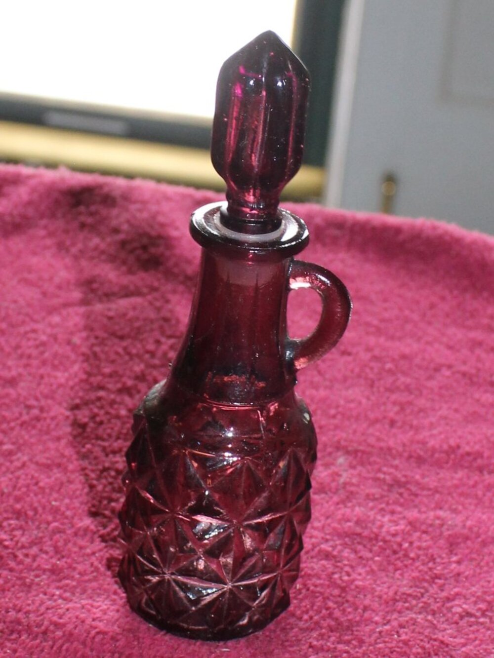 Vintage ruby red glass item appears to be an Avon brand mini decanter